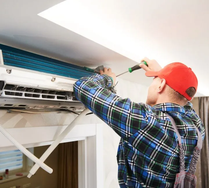 AC System Installation An expert installing an air conditioning unit in a house
