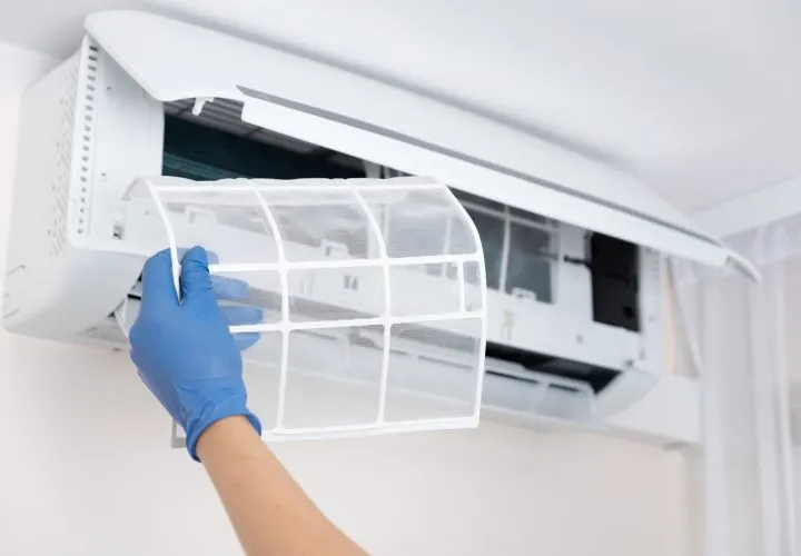 AC Maintenance A hand wearing latex gloves holding an air conditioning filter during the process of maintenance