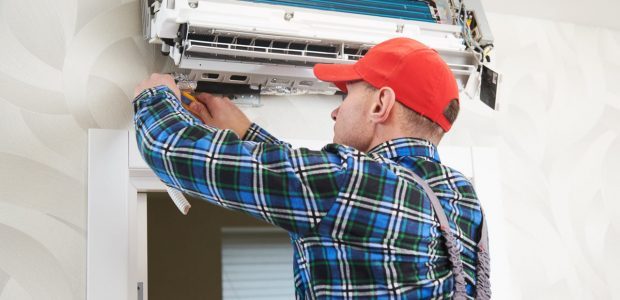 A skilled technician installing an air conditioning unit on the wall of a house